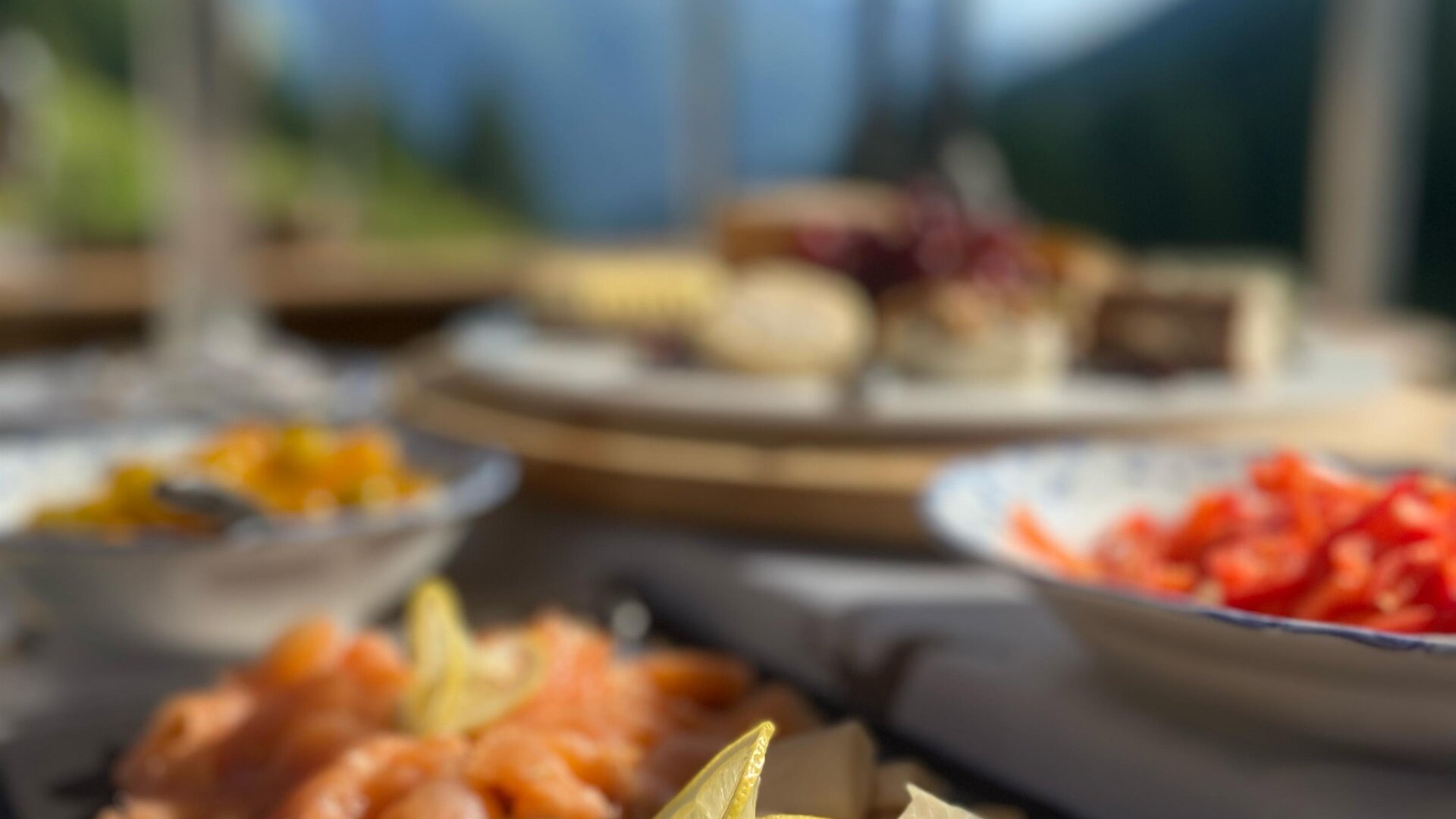 An attractively arranged selection of fish platters, garnished with lemon. In the background, other dishes and a beautiful landscape can be seen.