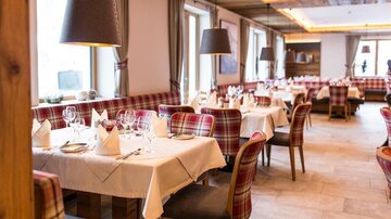 A stylish restaurant with elegant tables and checkered chairs.  
Large windows provide bright light and an inviting atmosphere.