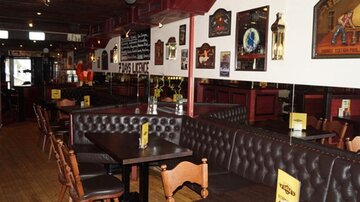 A cozy restaurant with leather benches and wooden tables. The walls are adorned with decorations and pictures.
