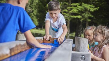 Kinder spielen an einem Wasserspielplatz im Freien. Sie haben Spaß, während sie mit Wasser und Sand experimentieren.