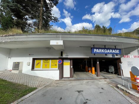 Eine Parkgarage mit einem Eingang und einem Schild, das "PARKGARAGE" anzeigt. Der Himmel ist blau mit einigen Wolken.
