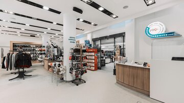 Ein moderner Einzelhandelsraum mit Kleidung und Accessoires. Die Auslagen sind ordentlich angeordnet, und die Wände sind hell gestaltet.