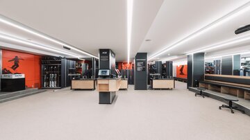 Ein moderner Verkaufsraum mit hellem, minimalistischen Design. An den Wänden sind Sportbekleidung und Ausrüstung ausgestellt.