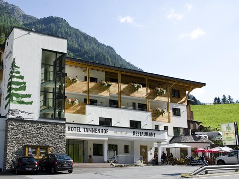 A cozy hotel with a modern and traditional design. There is a terrace with tables and chairs as well as a beautiful view of the surrounding mountains.