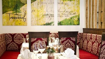 Ein gemütliches Restaurant mit elegant gedeckten Tischen. An der Wand hängen künstlerische Gemälde in sanften Farben.
