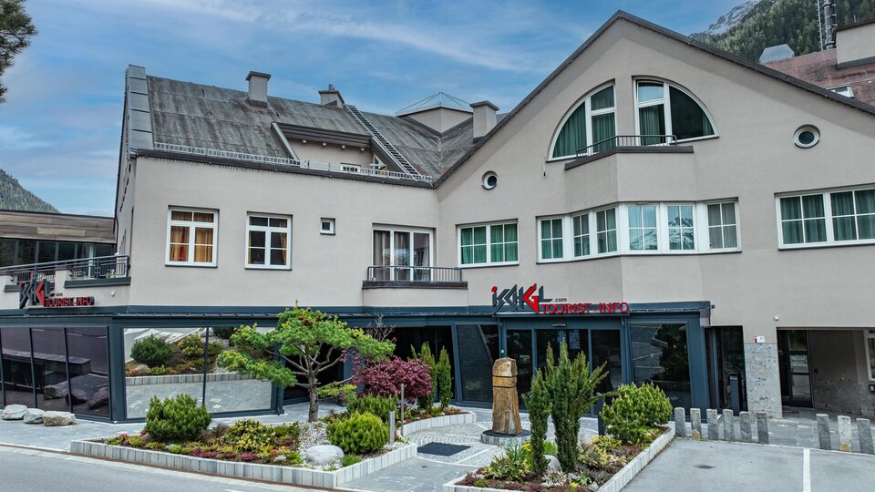 Ein modernes Gebäude mit einem Restaurantbereich und gepflegten Gartenanlagen. Die Architektur ist ansprechend und die Umgebung lädt zum Verweilen ein.