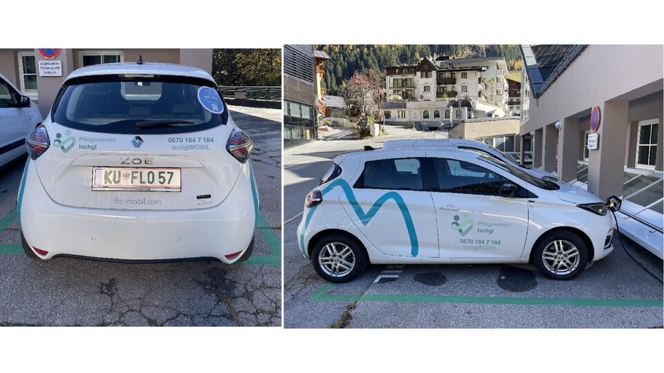 Ein weißes Auto mit Werbung auf der Seite parkt in einer Stadt. Die Umgebung zeigt Wohngebäude und eine saubere Straße.
